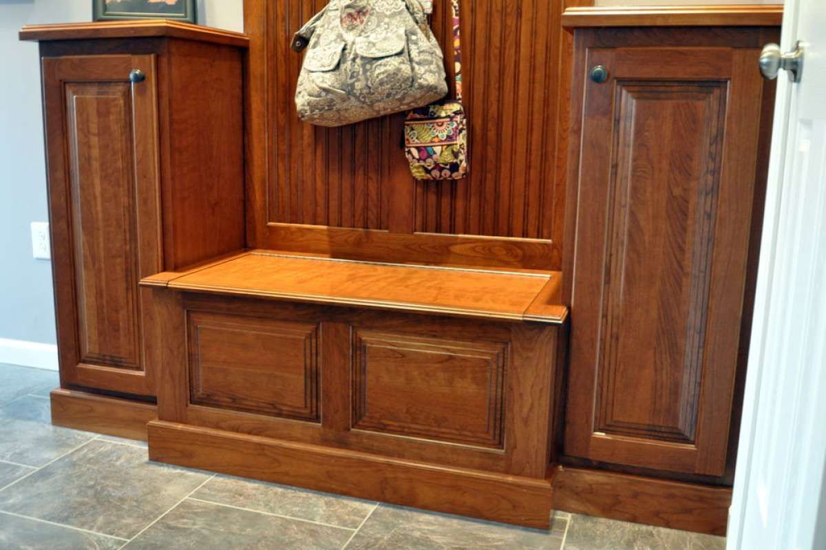 Wood-paneled church pew alcove with a small wooden bench and decorative wall hangings