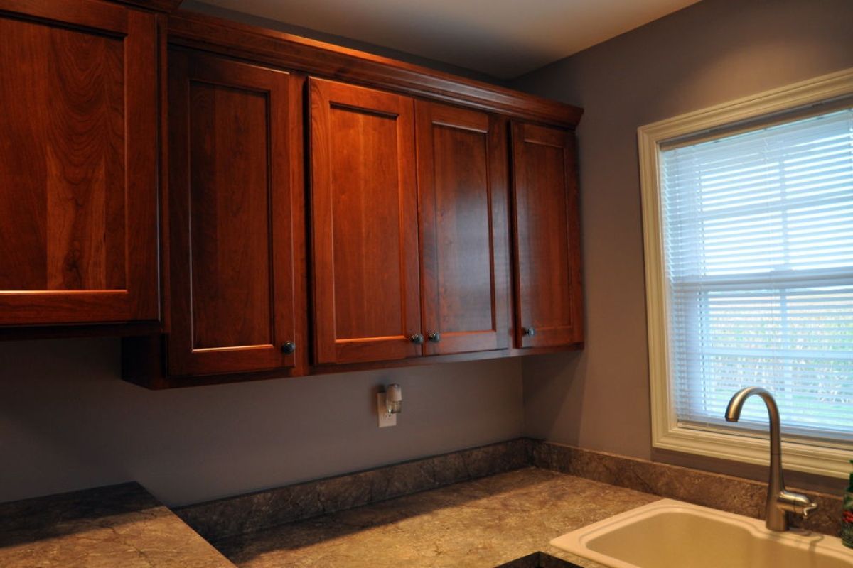 Wooden kitchen cabinets above a granite countertop beside a window over the sink.
