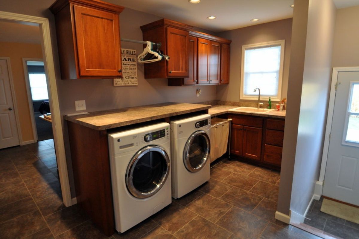 Laundry room with washer and dryer, wood cabinets, brown counters, and a window.