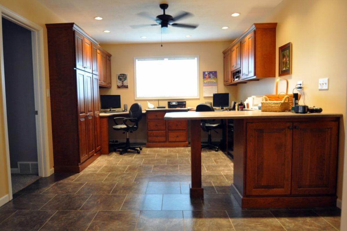 Modern kitchen with dark wood cabinets, large tiled floor, and a bright window at the back.