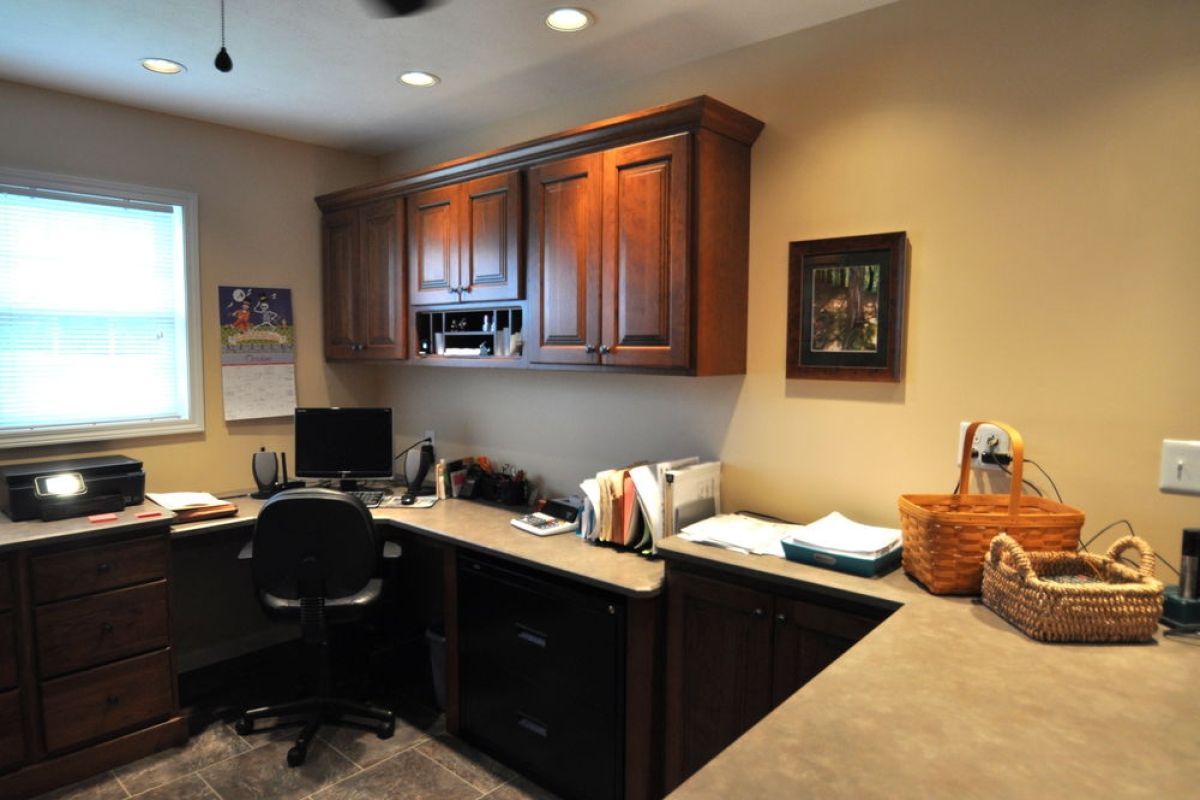 Home office with desk, chair, wood cabinets, and baskets under warm ceiling lights