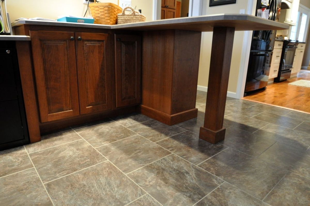 Kitchen with wood cabinets, tiled floor, and a wooden island table in the center