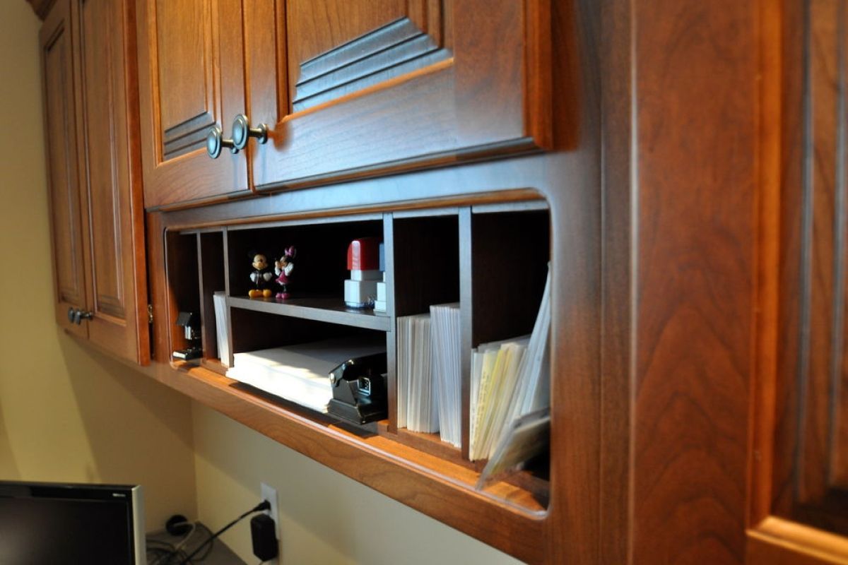 Wooden kitchen cabinets with an open cubby holding papers and small items above a countertop