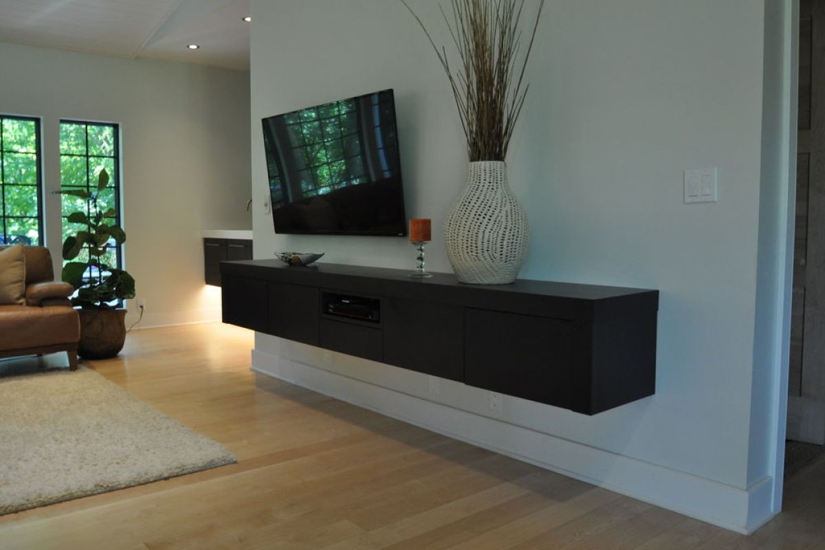 Modern living room with wall-mounted TV, black floating console, and large vase on a white shelf.