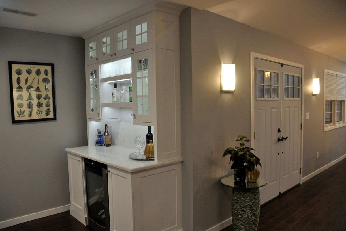 Bright hallway with white trim, framed art, wall sconces, and a small counter near a kitchen pass-through.