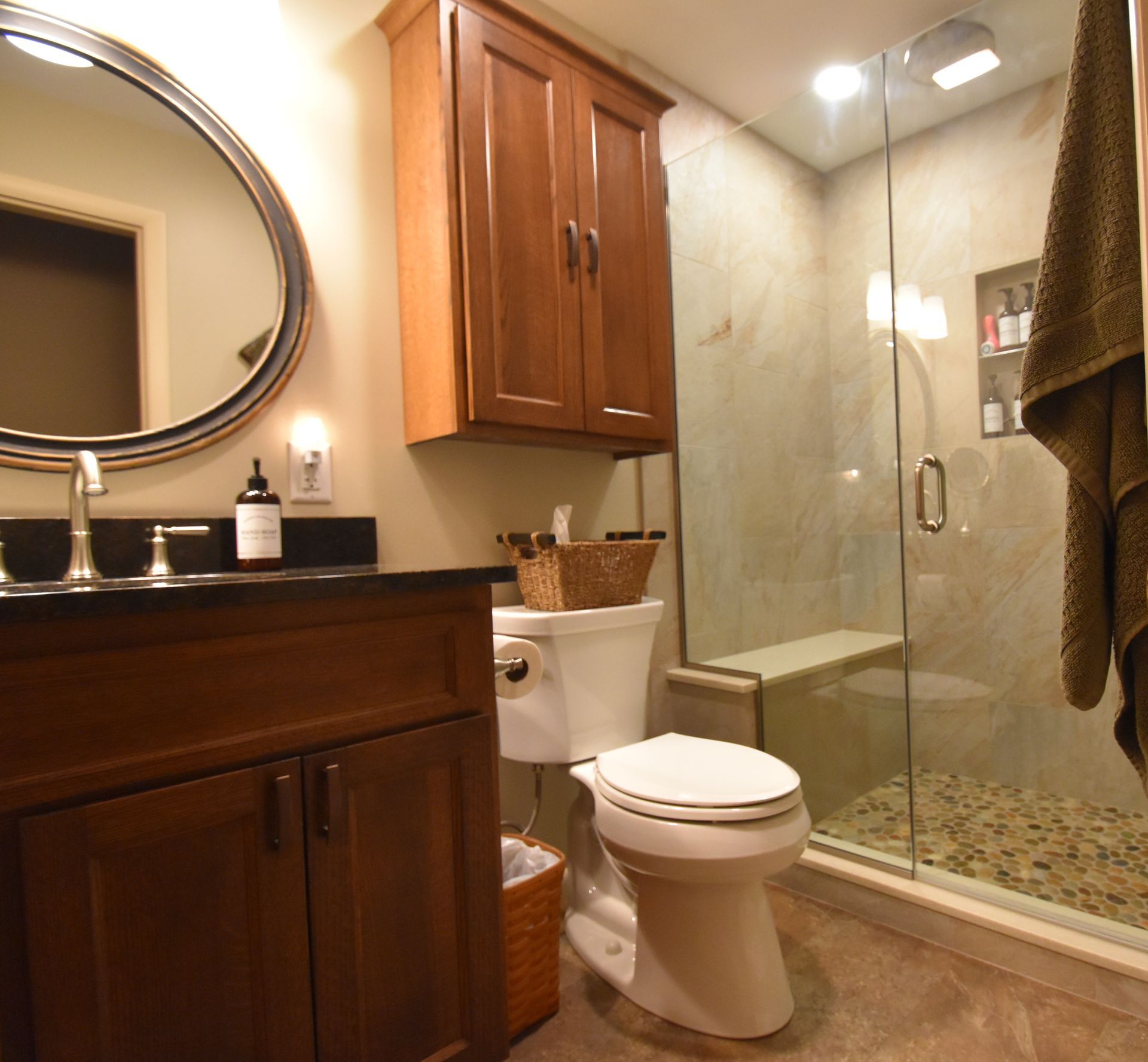 Modern bathroom with dark wood vanity, toilet, glass shower, and beige tile flooring