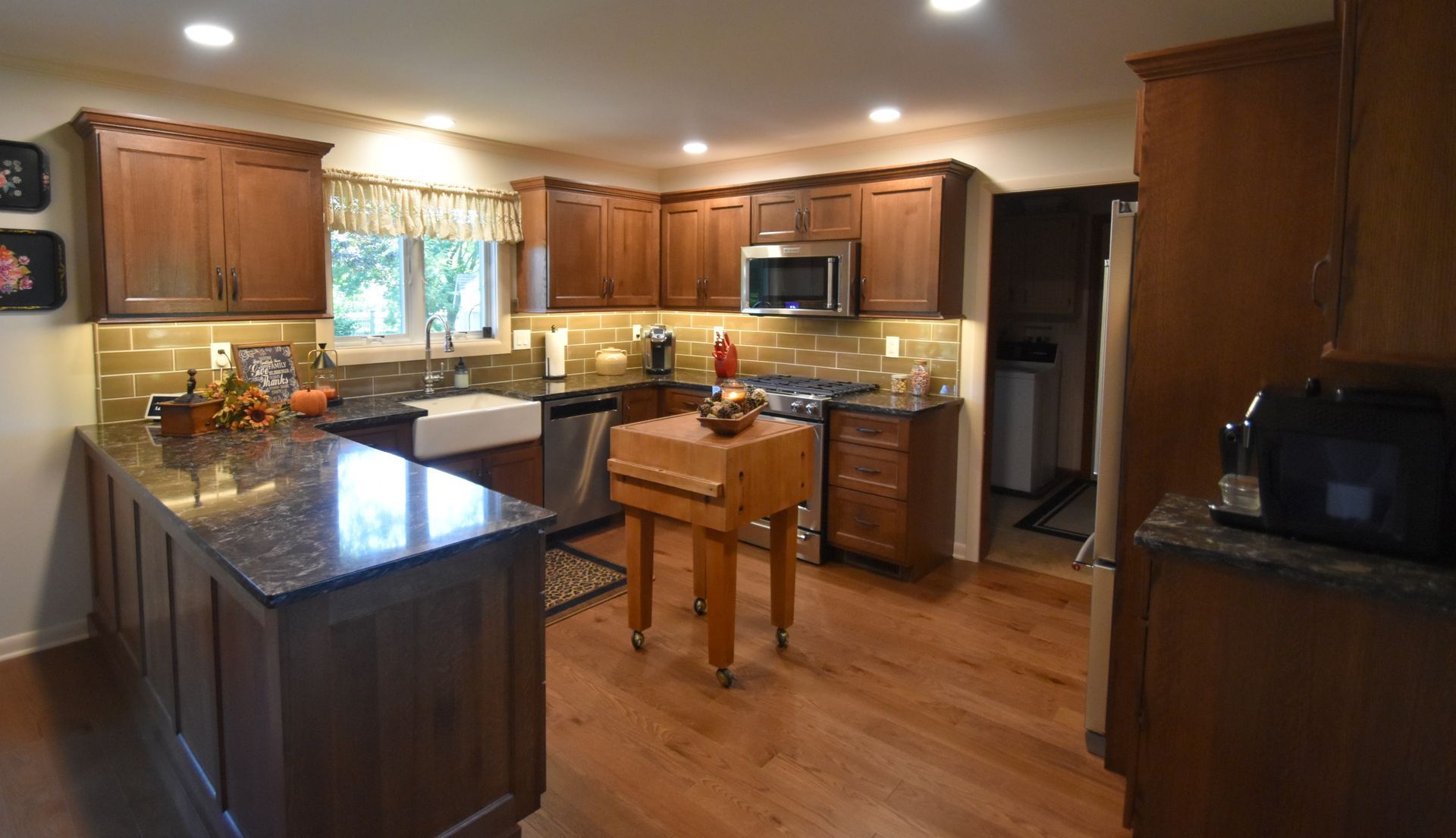 Spacious kitchen with wood cabinets, granite island, stainless appliances, and warm hardwood floors