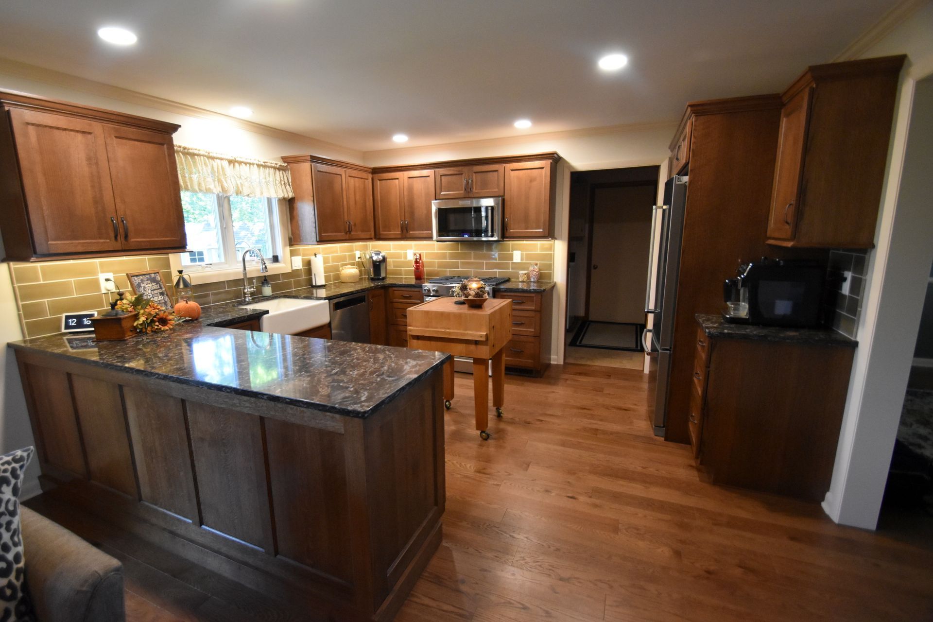 Warm kitchen with wood cabinets, granite island, stainless appliances, and hardwood floors
