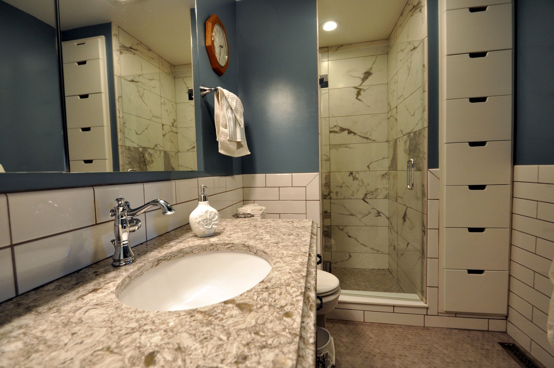 Bathroom with granite vanity, sink, mirror cabinets, blue walls, and glass shower stall