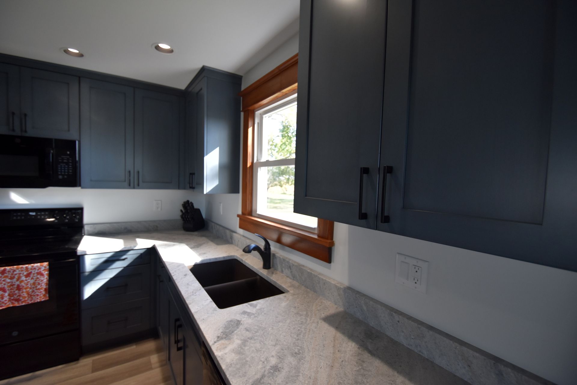 Modern kitchen with dark cabinets, white countertops, and a window over the sink
