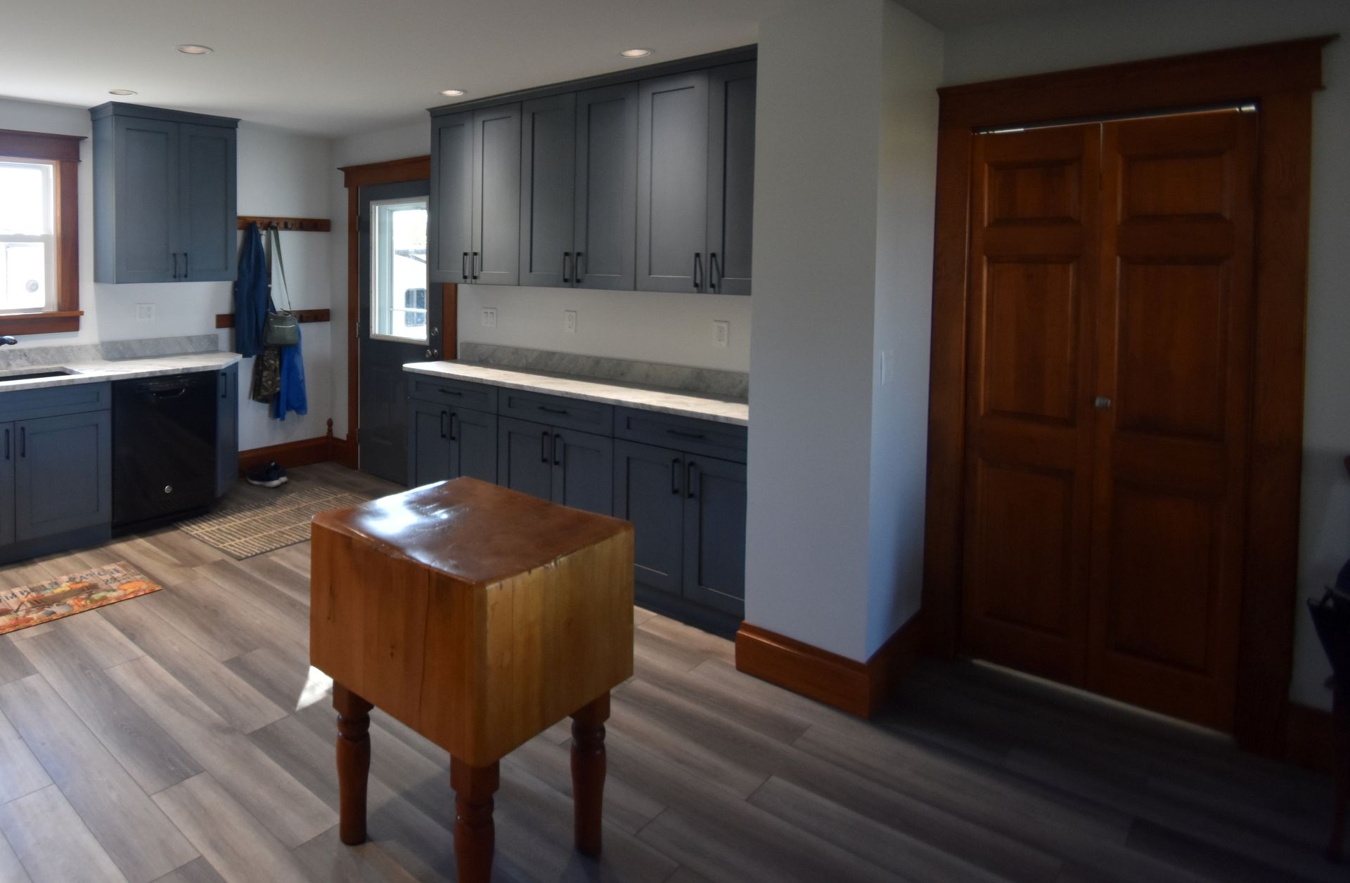 Modern kitchen with blue cabinets, wood floors, and a small wooden table in the foreground