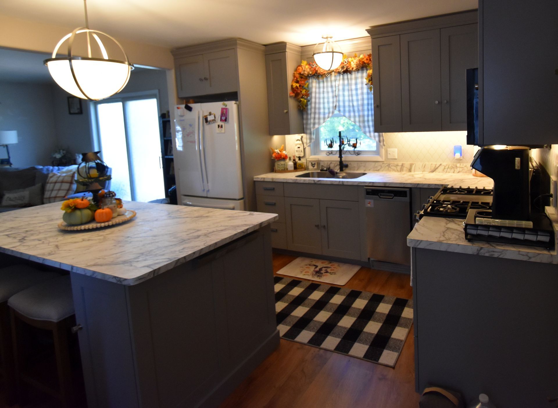Modern kitchen with gray cabinets, marble island, white refrigerator, and black-and-white rug
