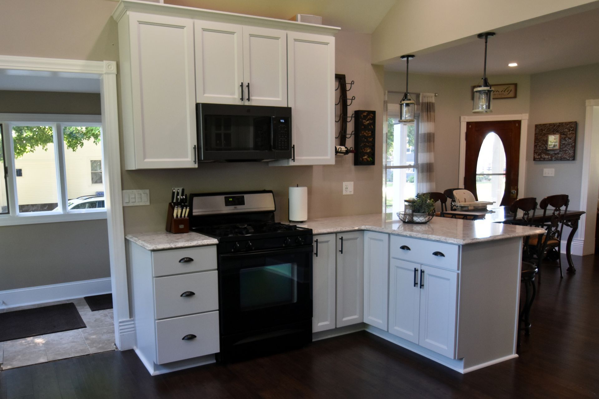 Bright kitchen with white cabinets, black appliances, and a peninsula overlooking a dining area