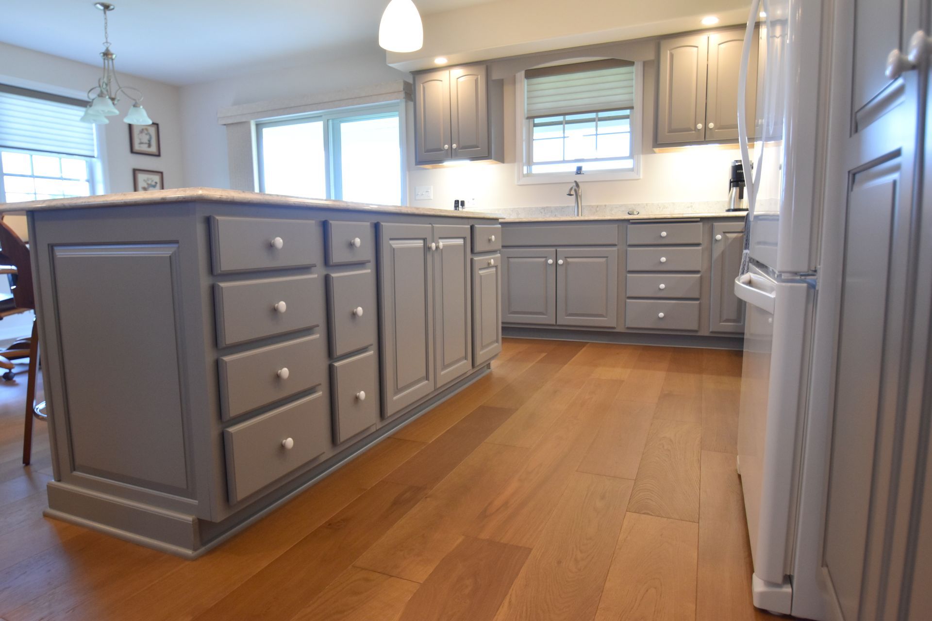 Modern kitchen with gray cabinets, hardwood floors, and an island under bright windows