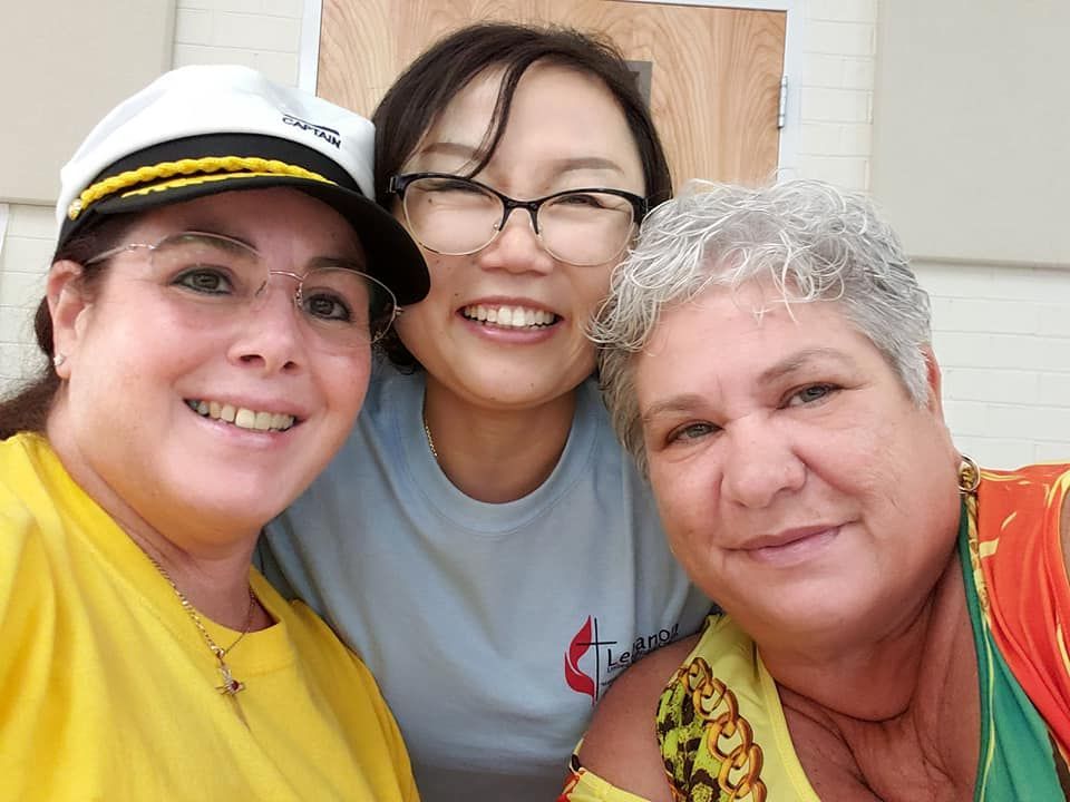 Three women posing for a picture with one wearing a captain 's hat