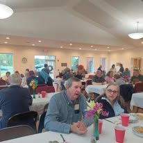A group of people are sitting at tables in a large room.