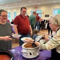 A group of people are standing around a table eating food.