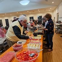A group of people are standing around a table eating food.