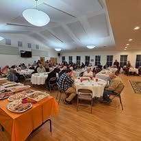 A large group of people are sitting at tables in a large room.