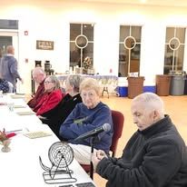 A group of people are sitting at a table playing bingo.
