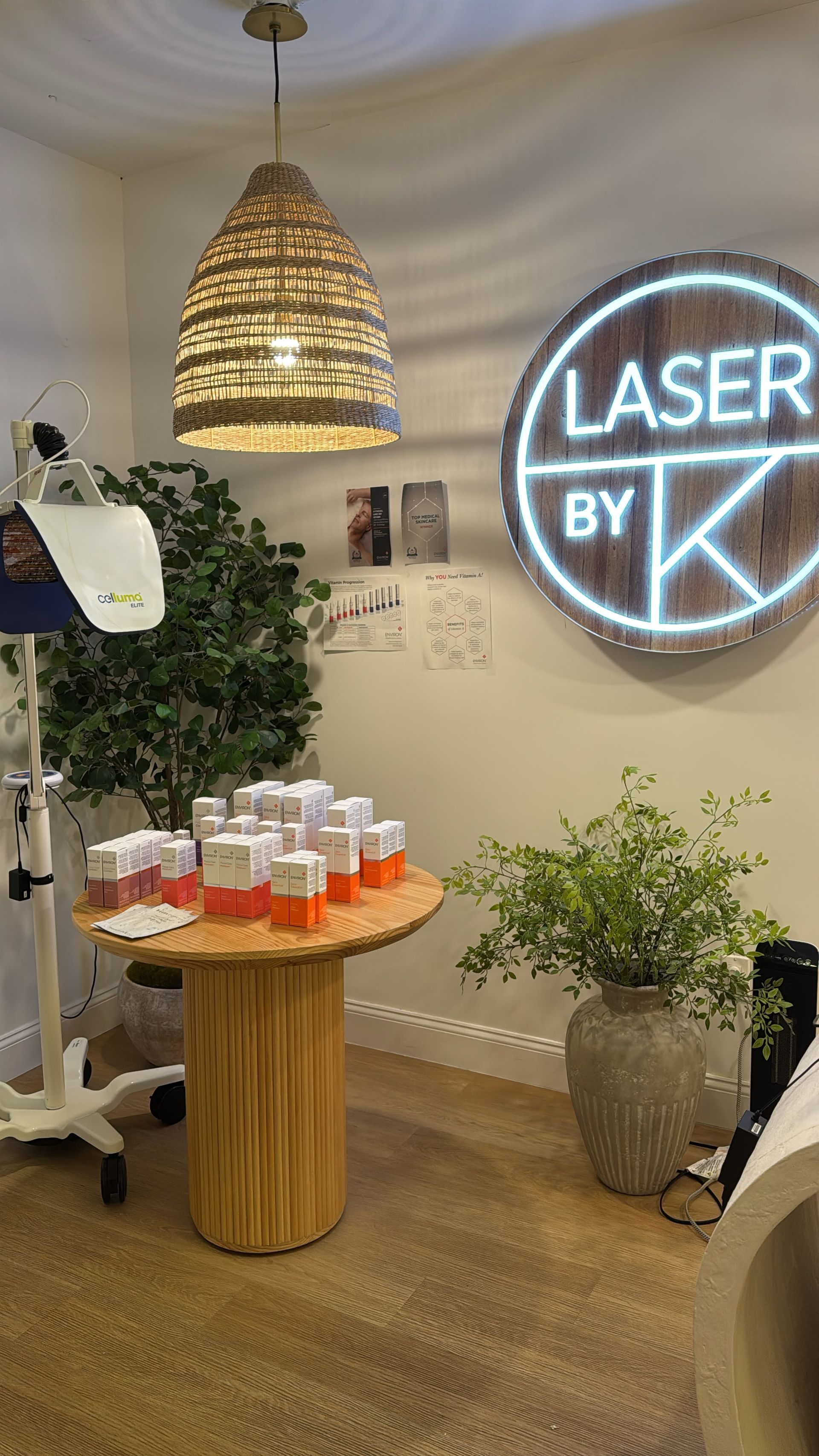 Laser By K neon sign above the wood table and skincare display