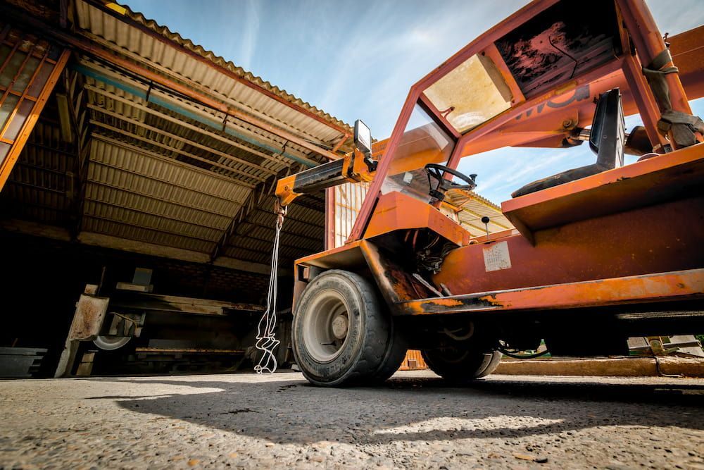 An Orange Forklift Is Parked In Front Of A Building — Caloundra Scrap Metal in Caloundra West, QLD