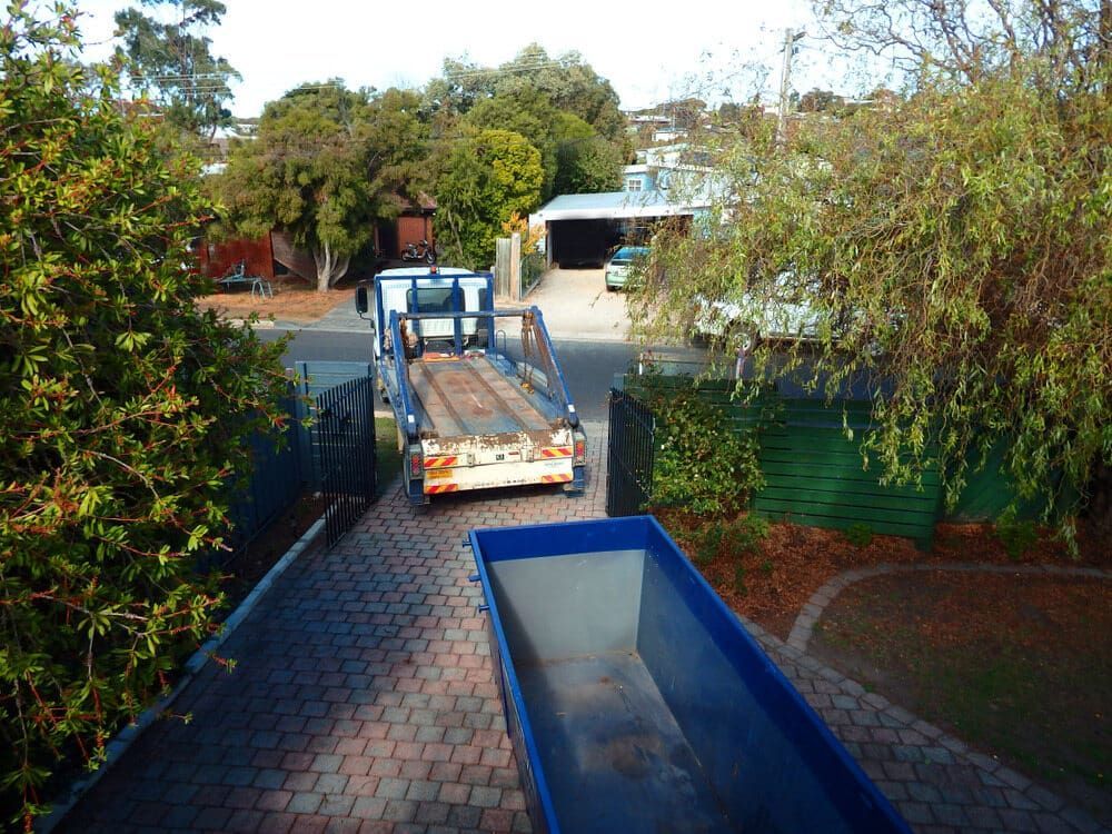 A Blue Dumpster Sits Next To A Truck On A Driveway — Caloundra Scrap Metal in Maroochydore, QLD