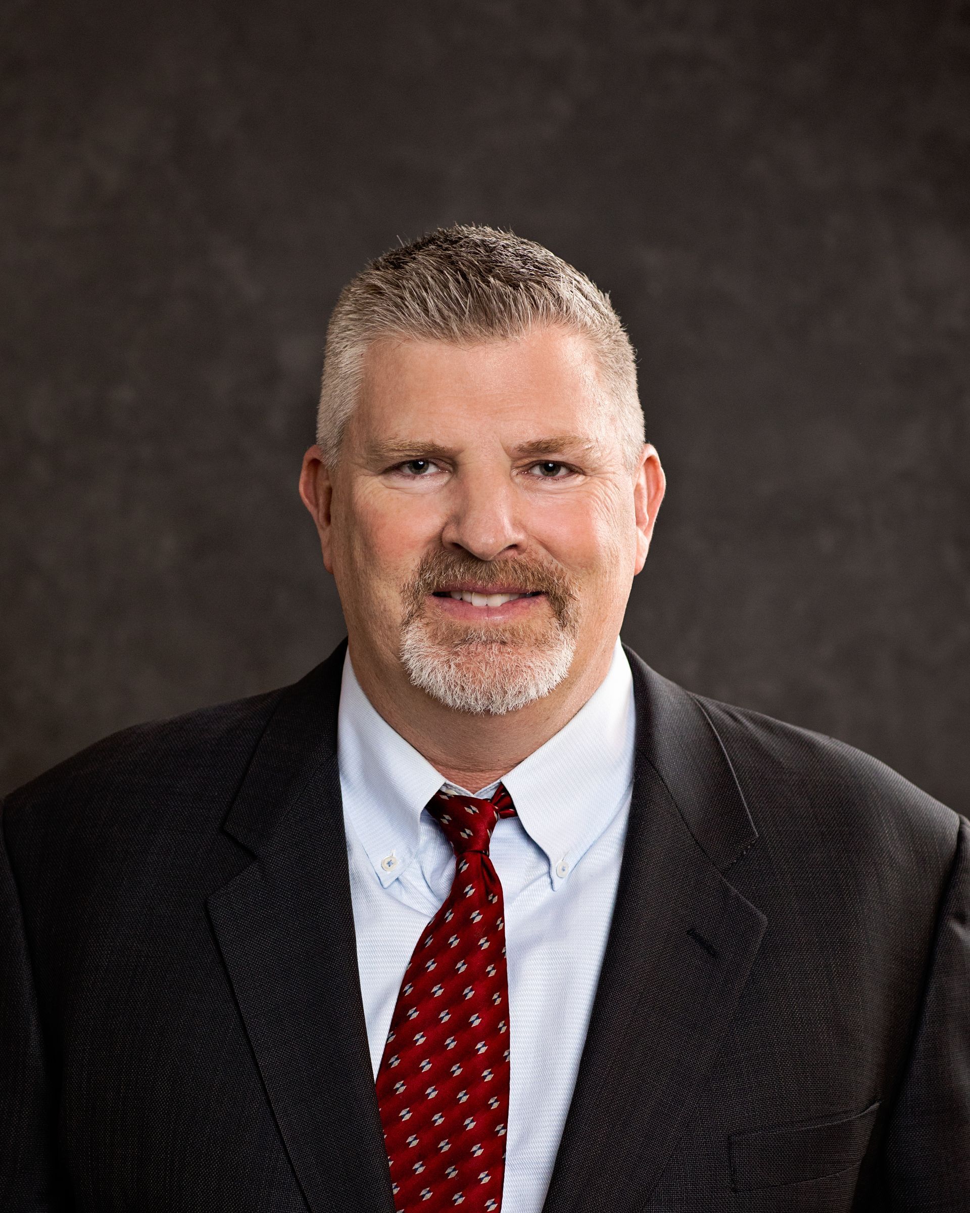 A man in a suit and tie is smiling for the camera.