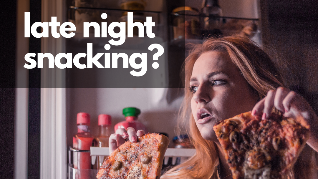 A woman is eating a slice of pizza in front of a refrigerator.