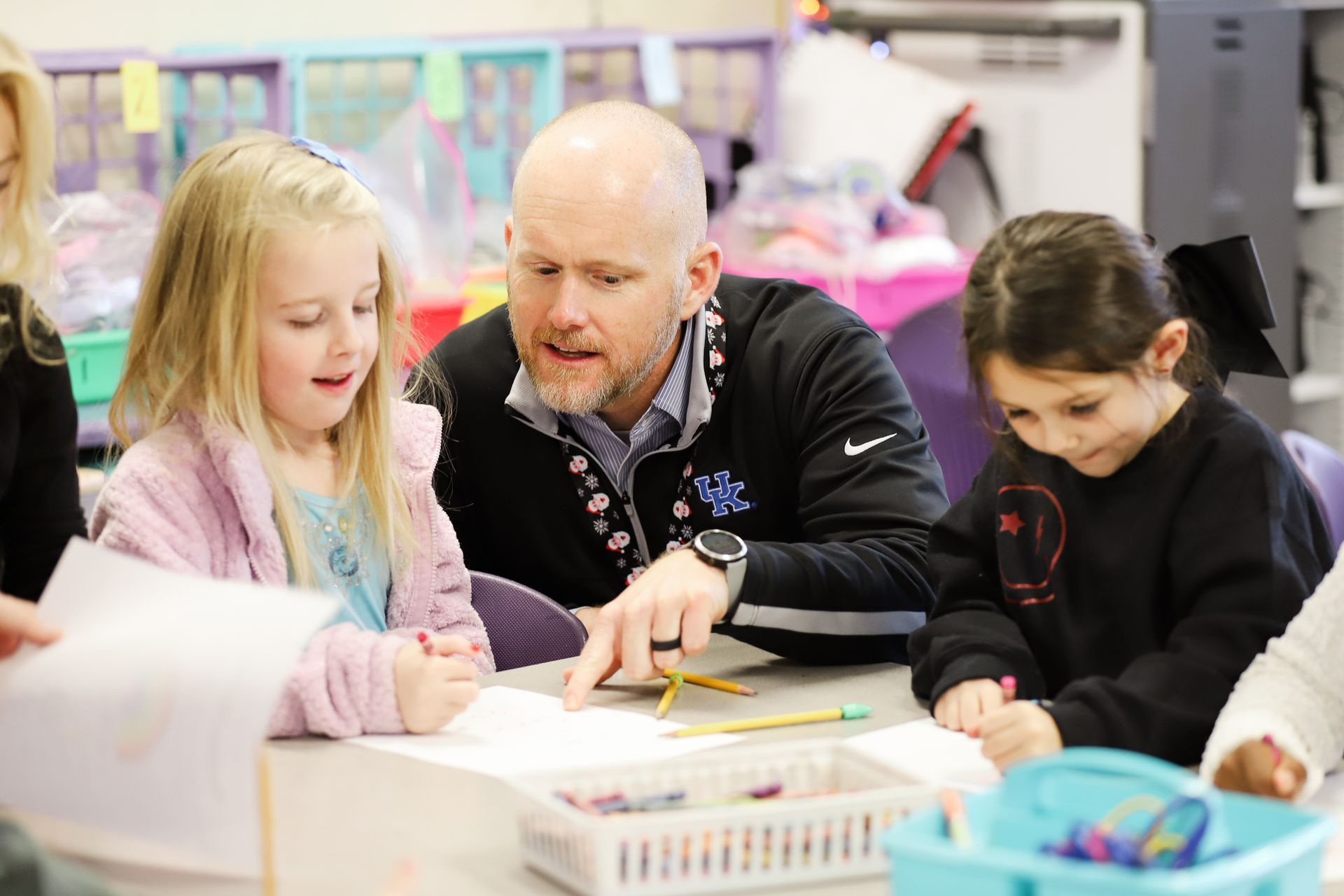 A man is teaching a group of young girls in a classroom.