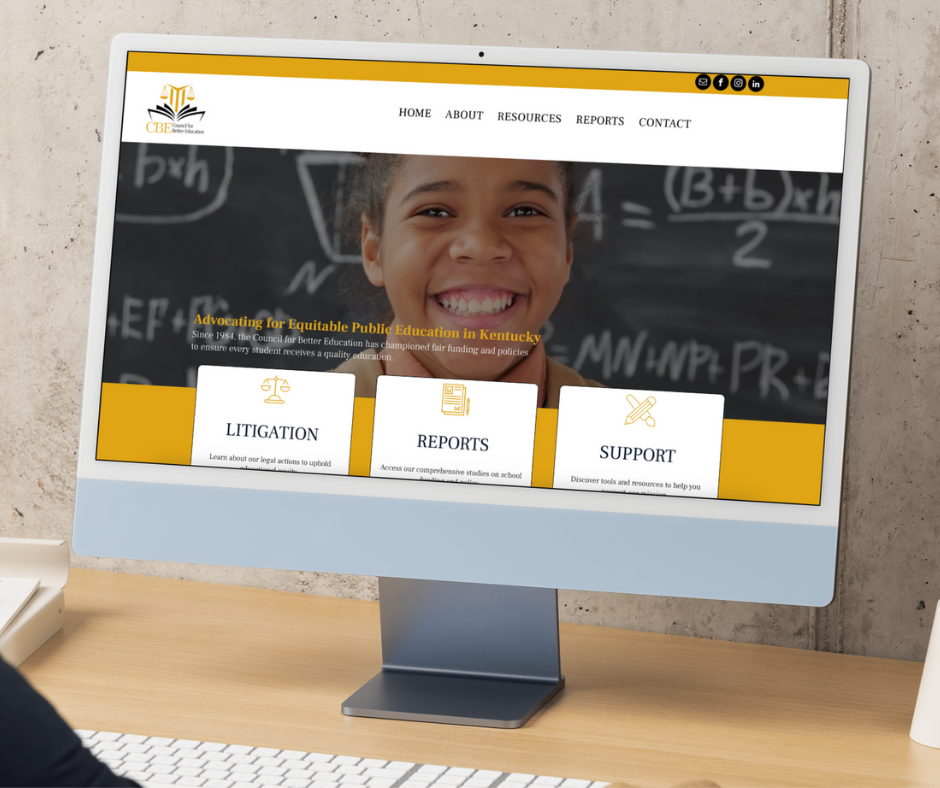 A desktop monitor on a wooden desk displays the Council for Better Education (CBE) website homepage, featuring a smiling student in front of a chalkboard and the tagline 
