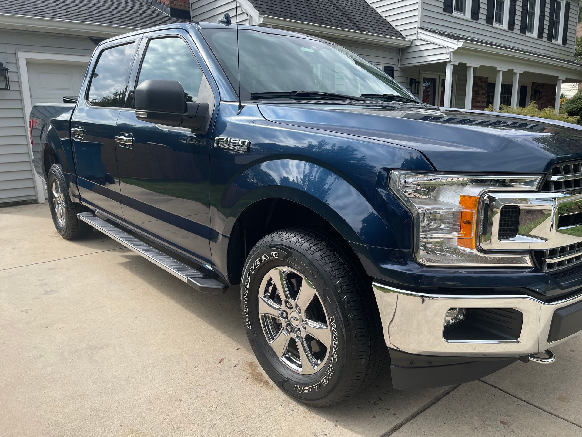 Blue Ford F-150 pickup truck parked in driveway with glossy paint, clean wheels, and fresh exterior detailing