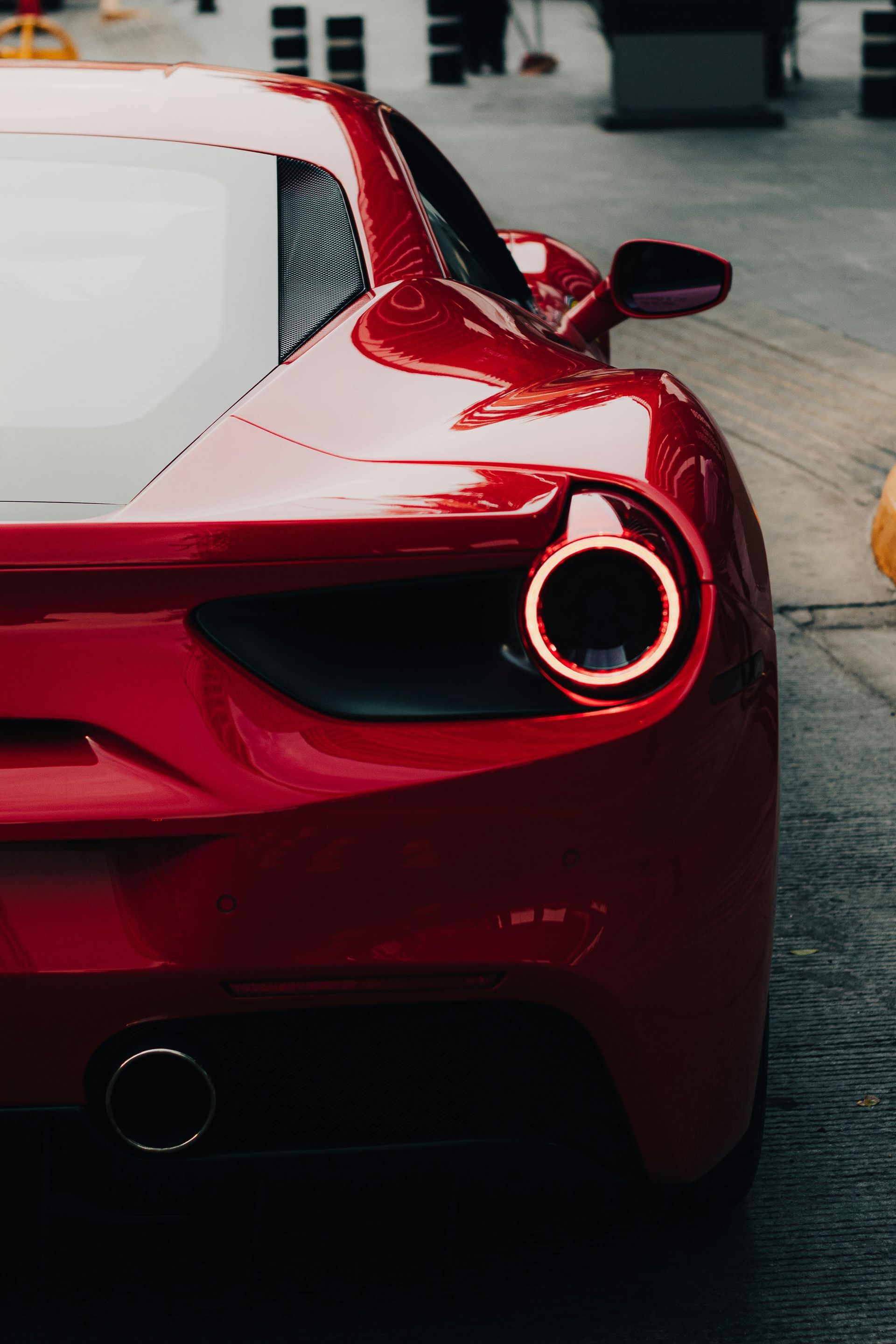 Rear mobile  detail of a red sports car  with chrome surround on a polished red exotic car.