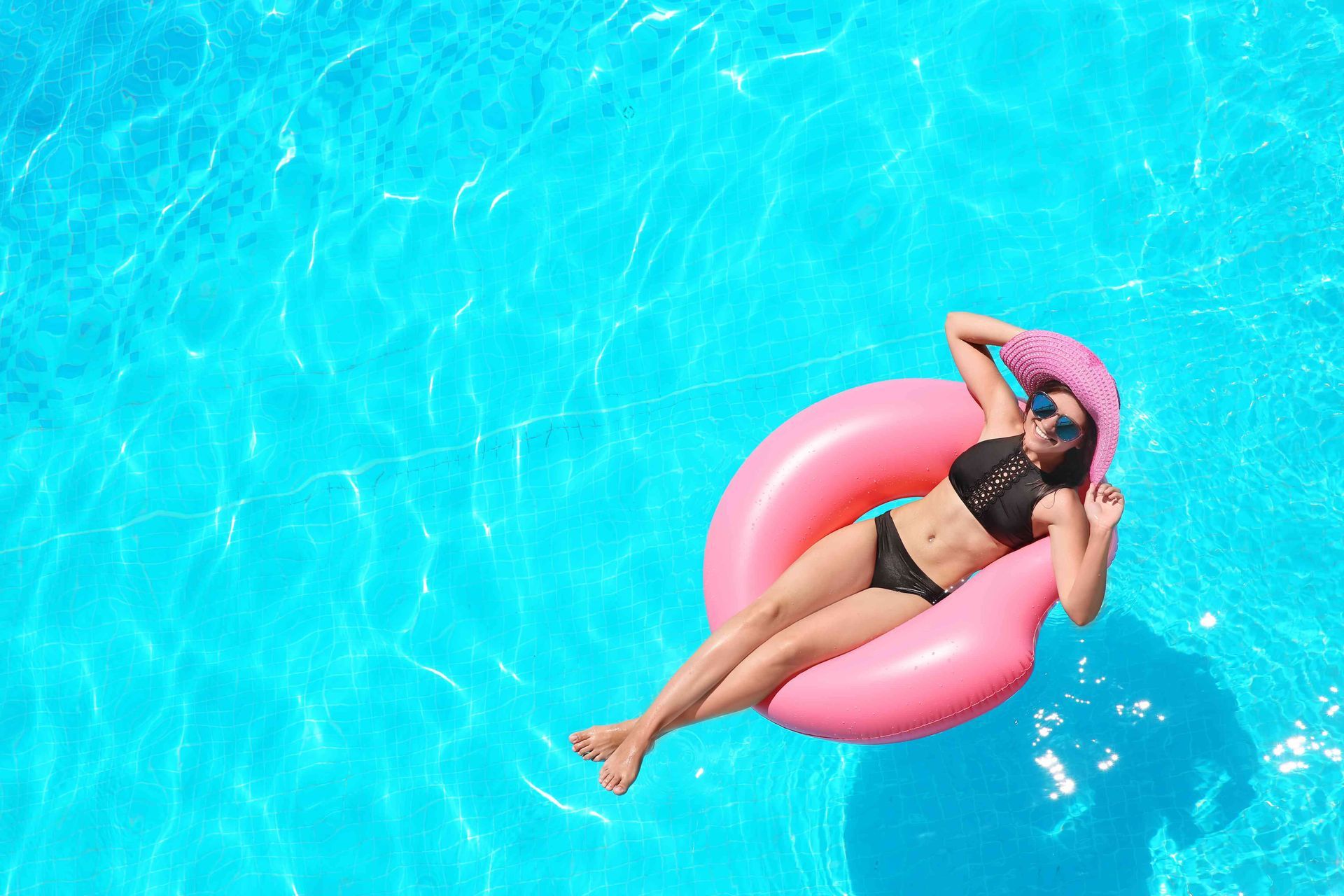 A woman in a hat sitting on an intertube.