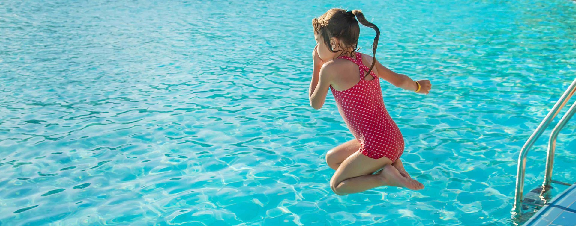 A kid doing a cannonball into a swimming pool