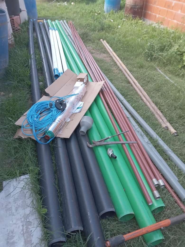Sobre el césped yacen tuberías de distintos colores y tamaños, junto con otros materiales de fontanería.