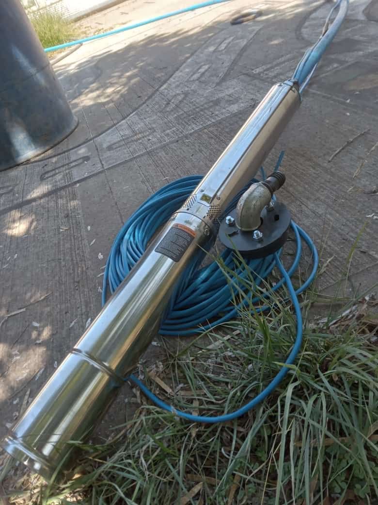 Bomba de pozo de agua sumergible con cable azul en un tocón de árbol.