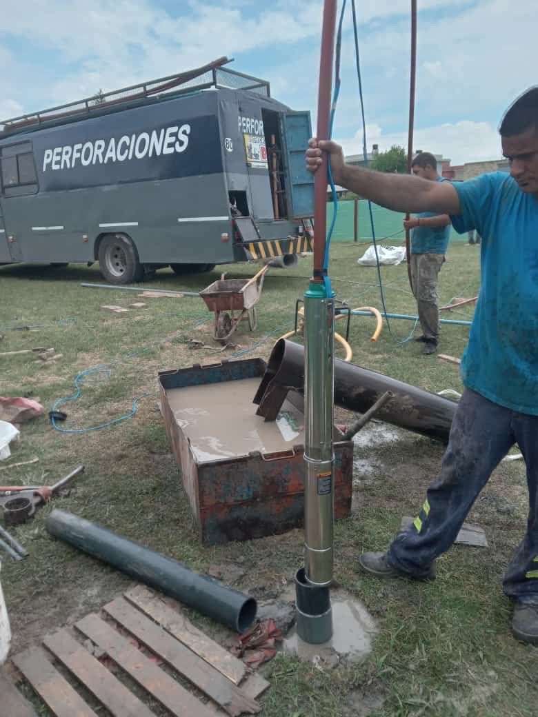 Hombre instalando una bomba de pozo de agua al aire libre, camión con