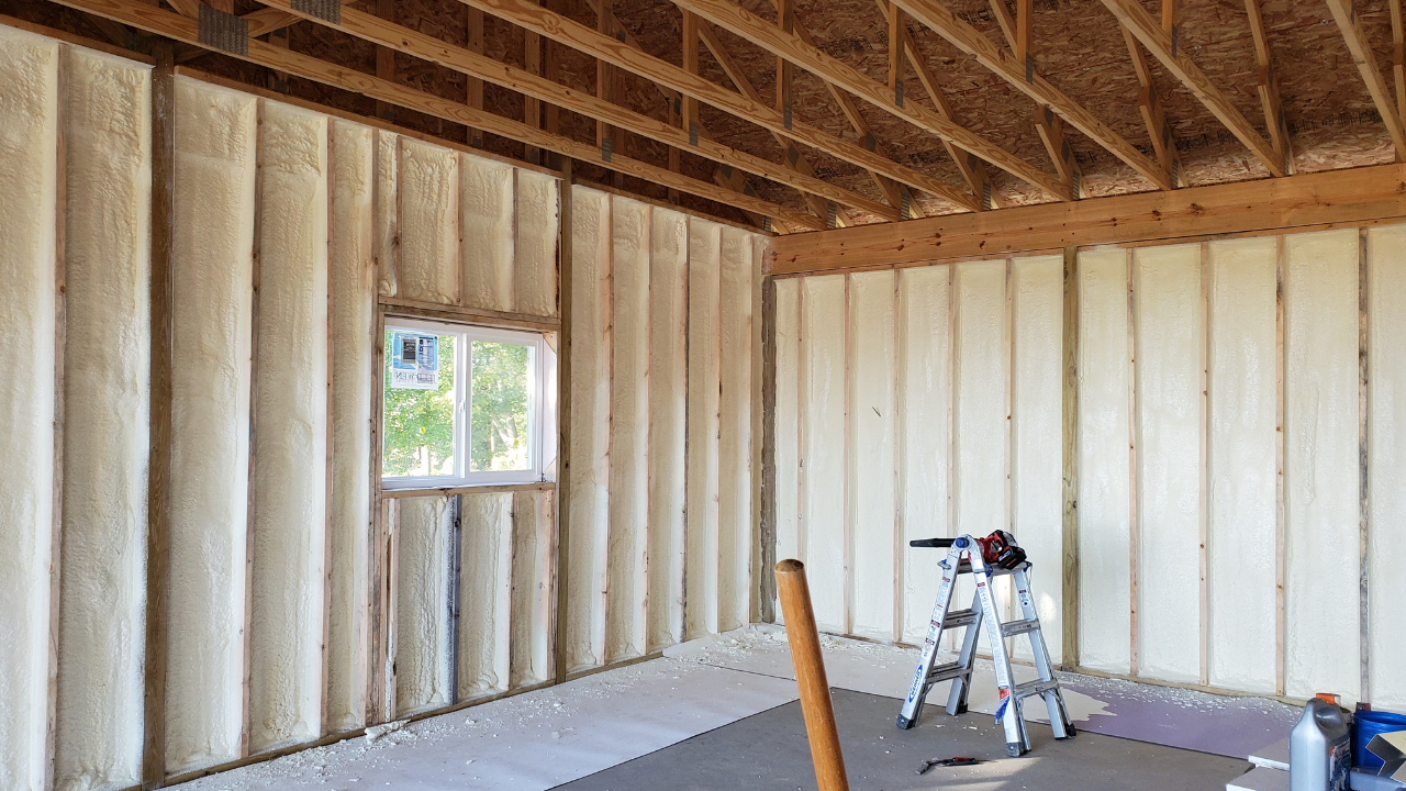 Unfinished room with exposed wall studs, a small window, and a step ladder near the back wall.