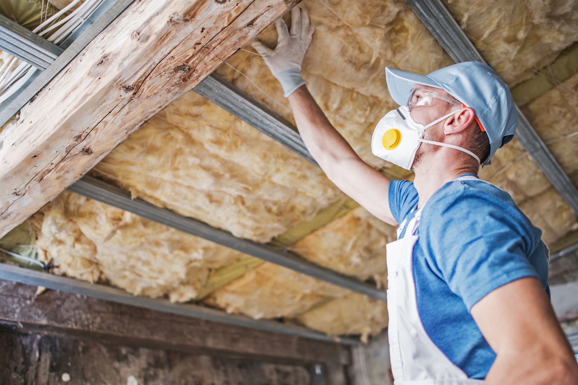 Person sprays green foam insulation in a wood-framed ceiling.