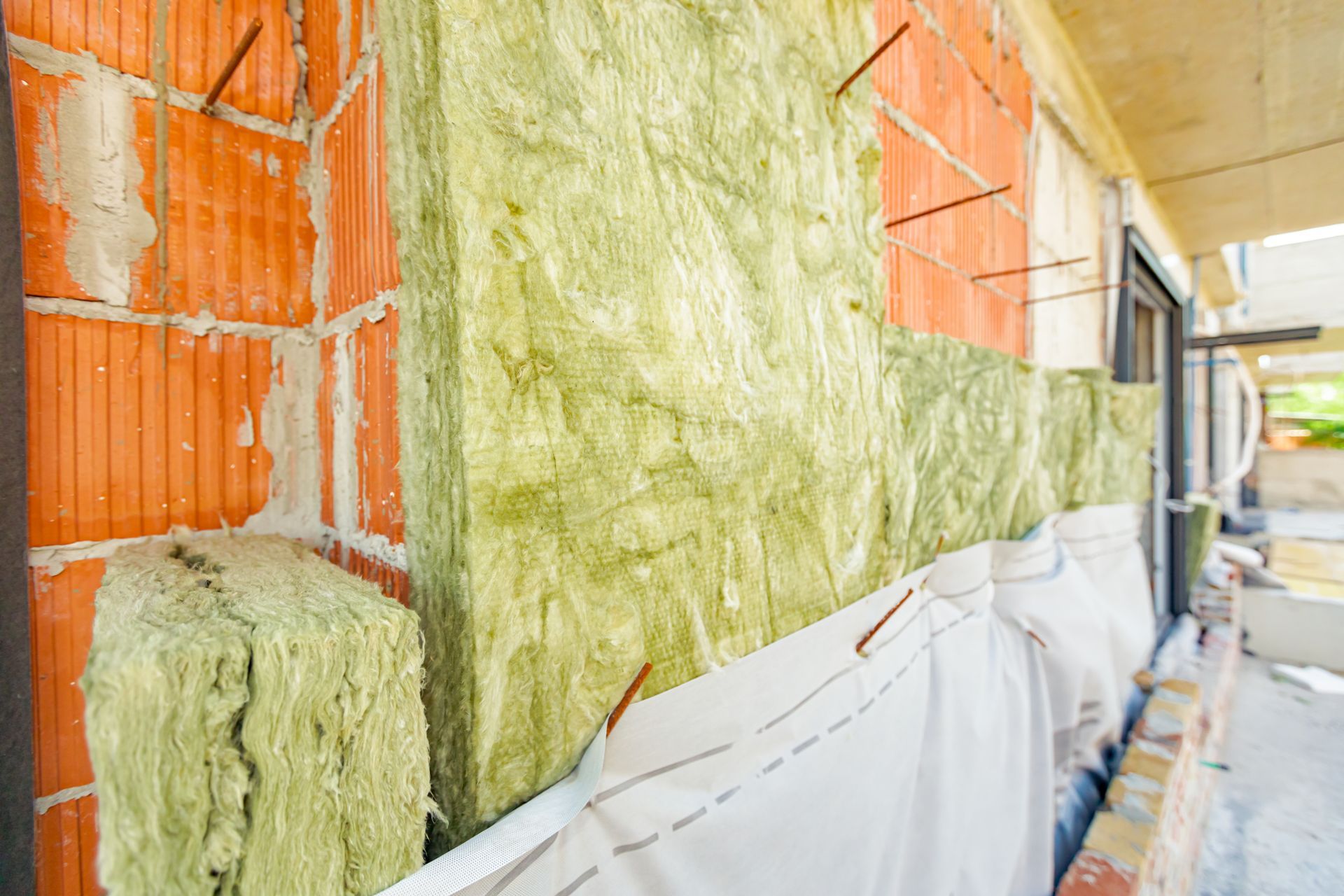 Exterior wall under construction with insulation between brick and siding.