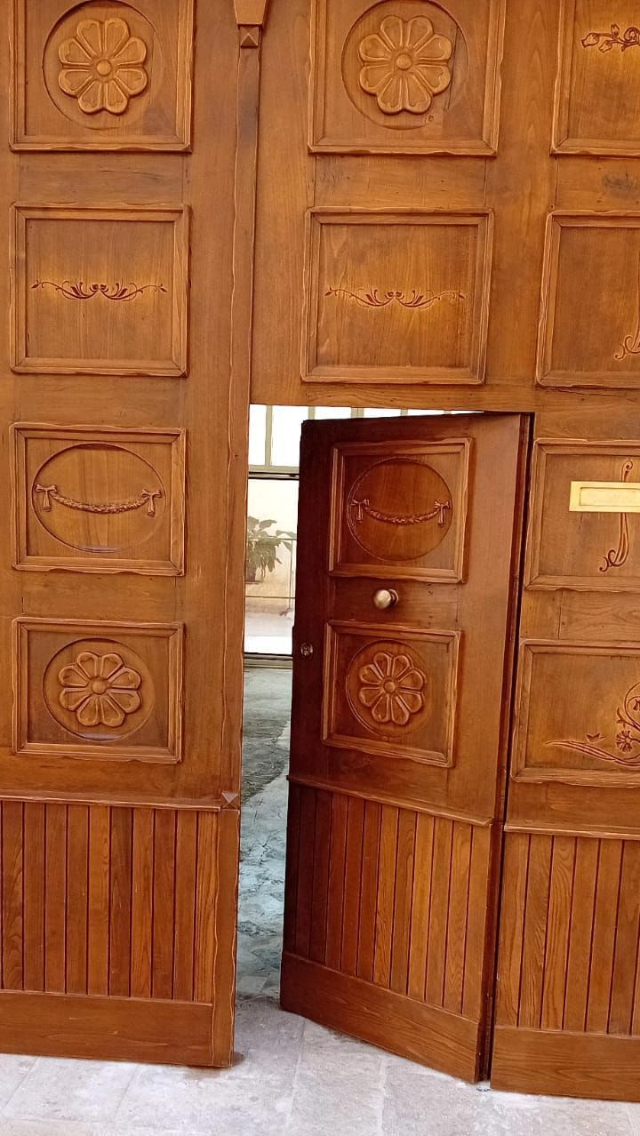 Una porta di legno con un disegno floreale è aperta.