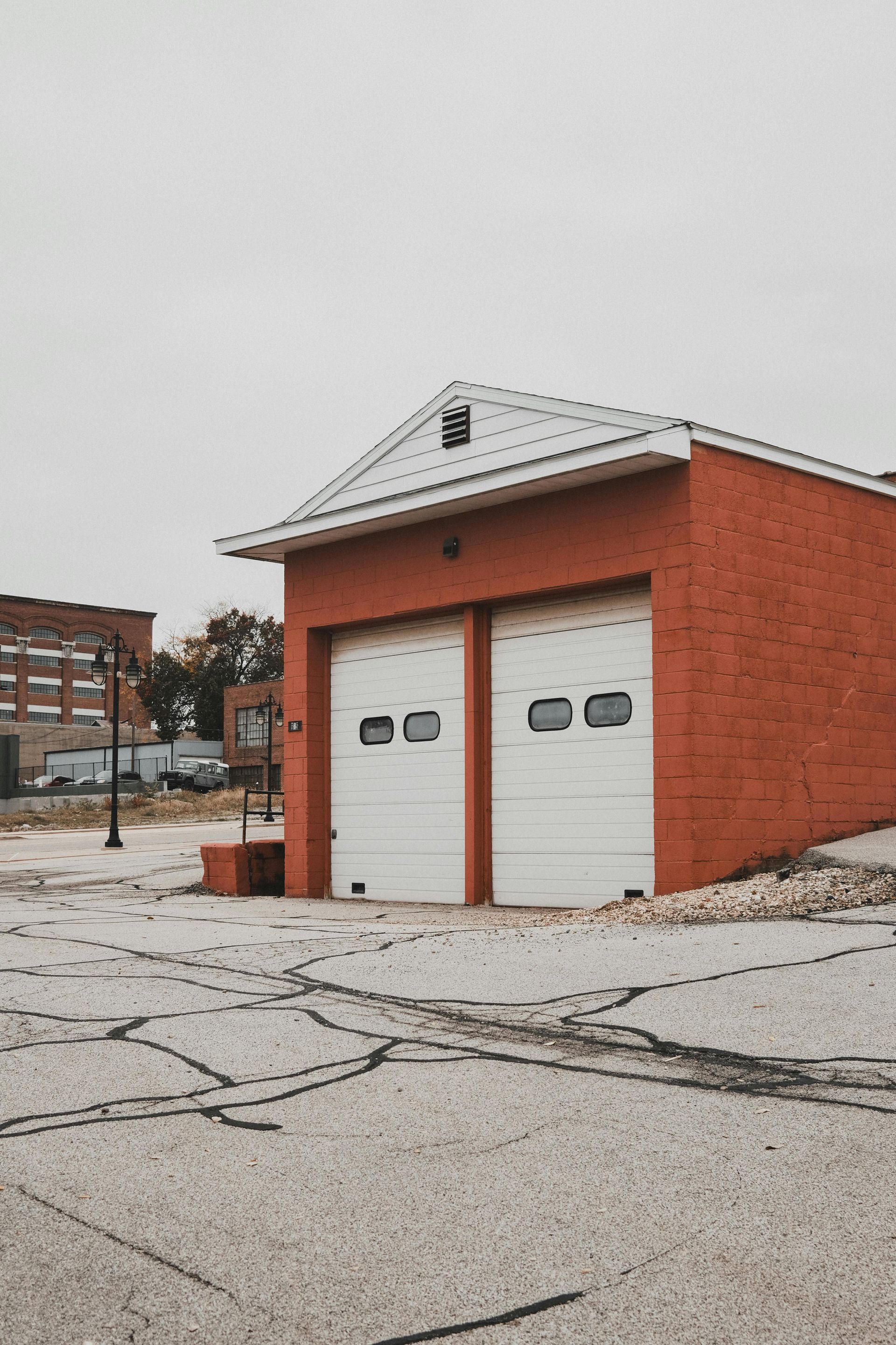 A red brick garage with two white garage doors