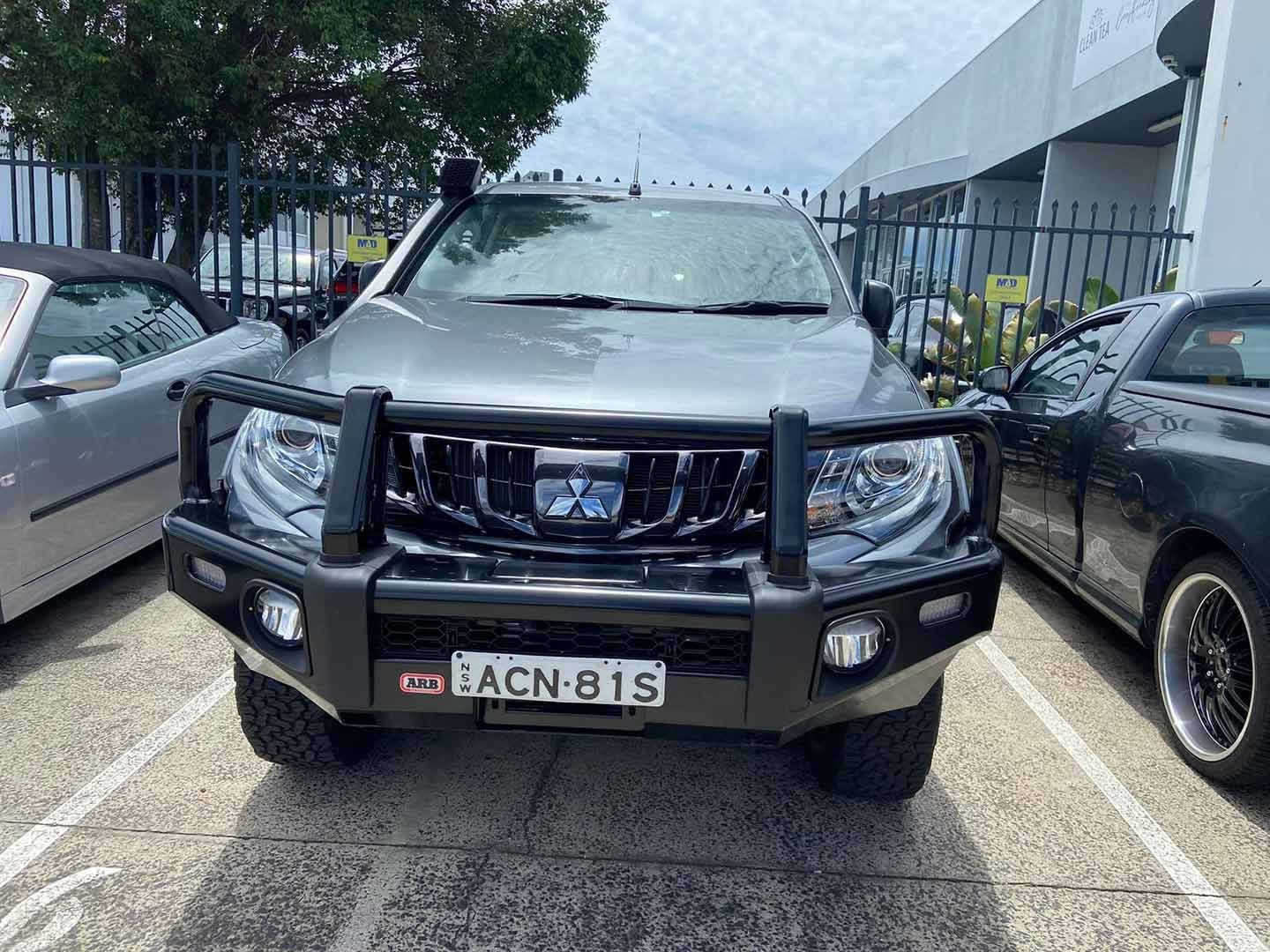 A Mitsubishi Pickup Truck Is Parked in A Parking Lot Next to Other Cars — Motor Accessories Direct In Tweed Heads South, NSW