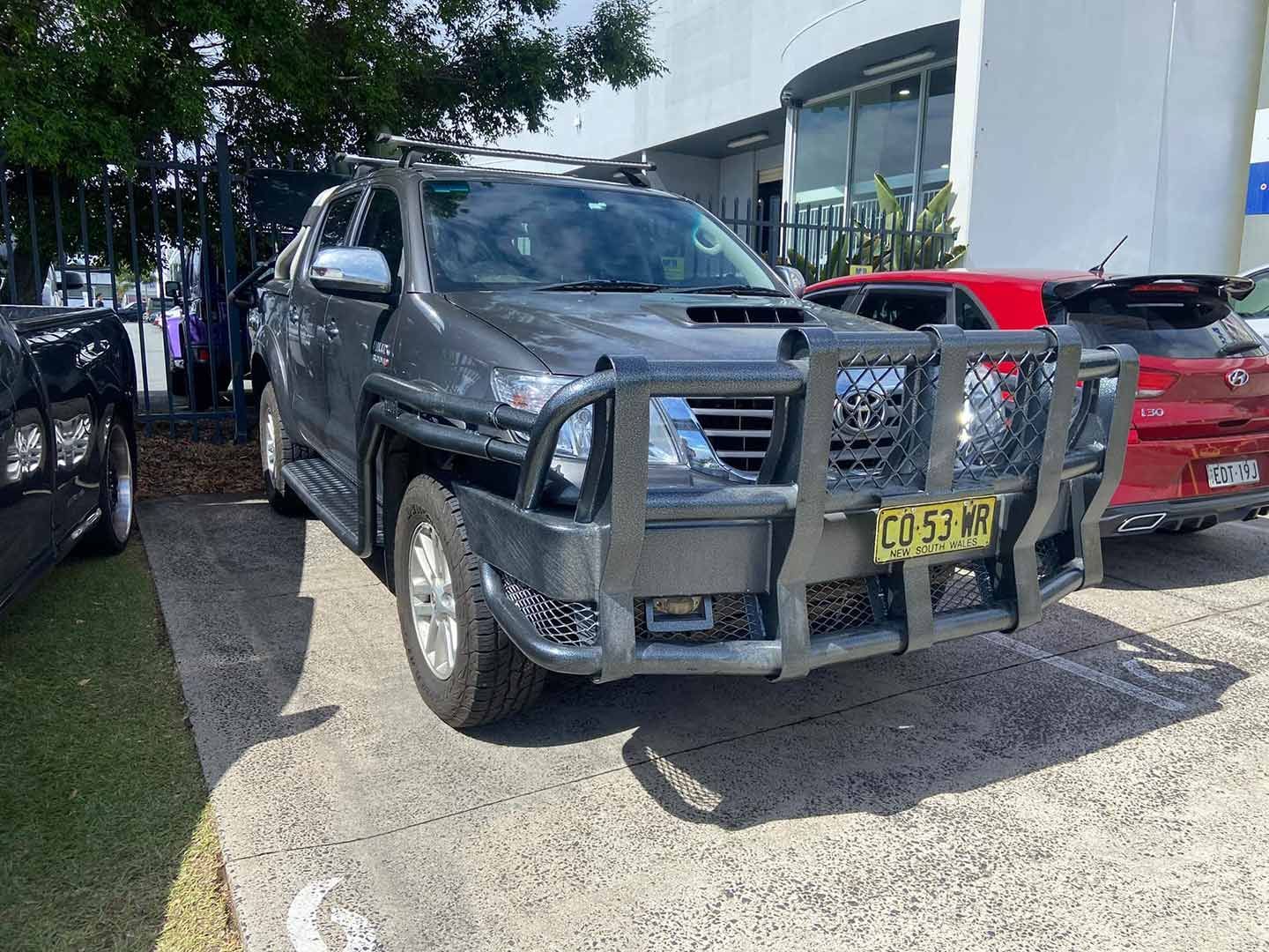A Toyota Hilux Is Parked in A Parking Lot in Front of A Building — Motor Accessories Direct In Tweed Heads South, NSW
