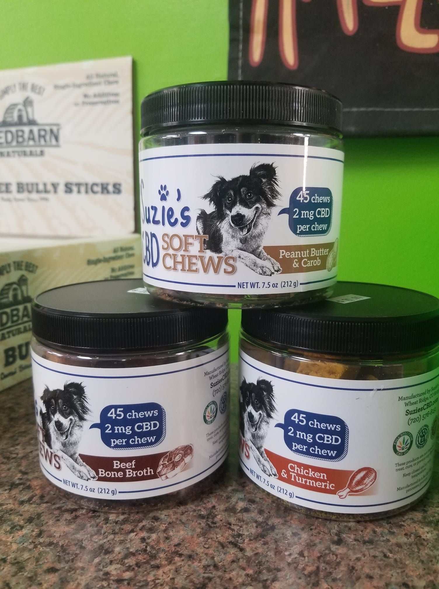 Three jars of dog chews are stacked on top of each other on a table.