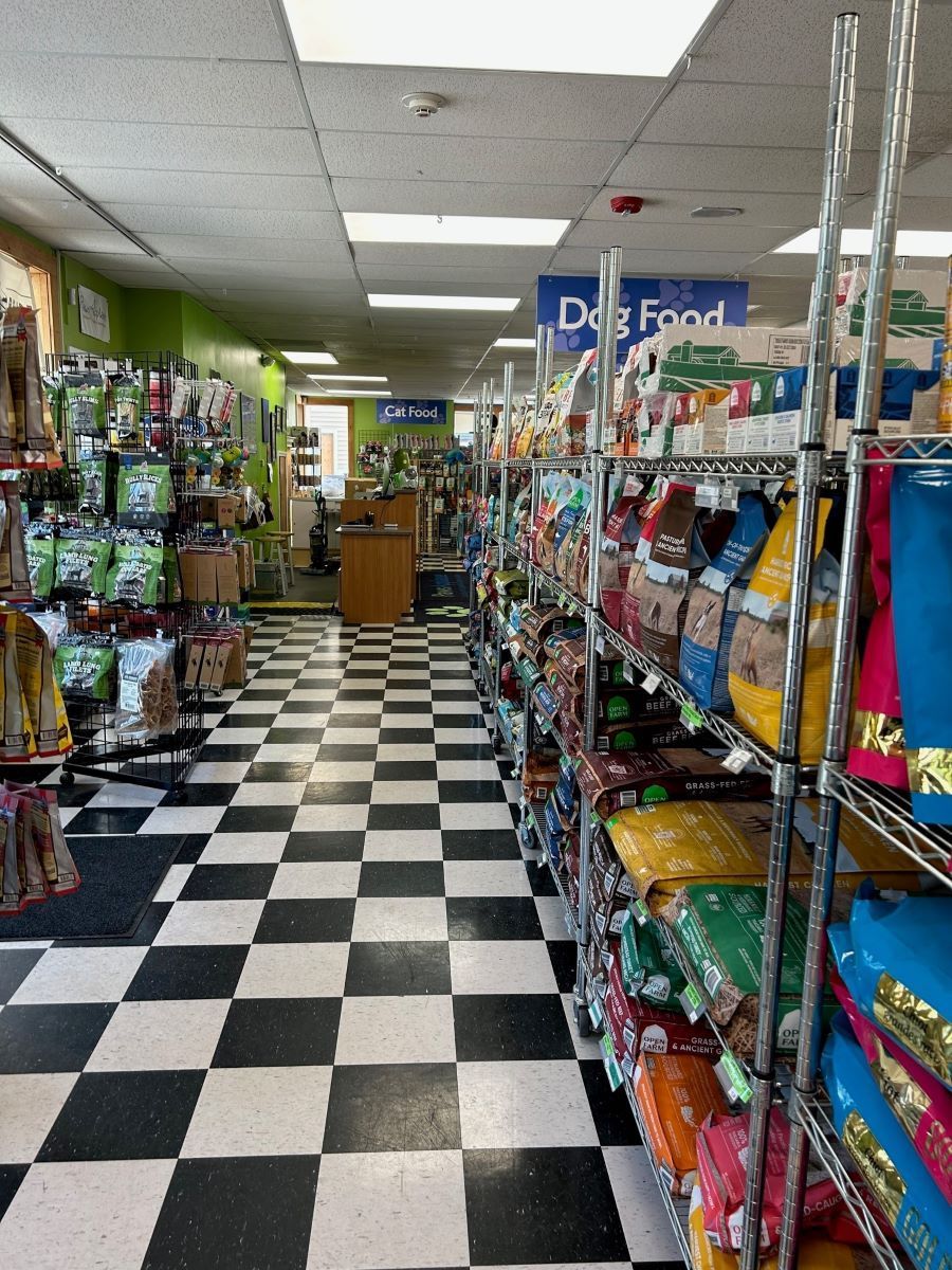 The inside of a pet store with a checkered floor and shelves filled with dog food.