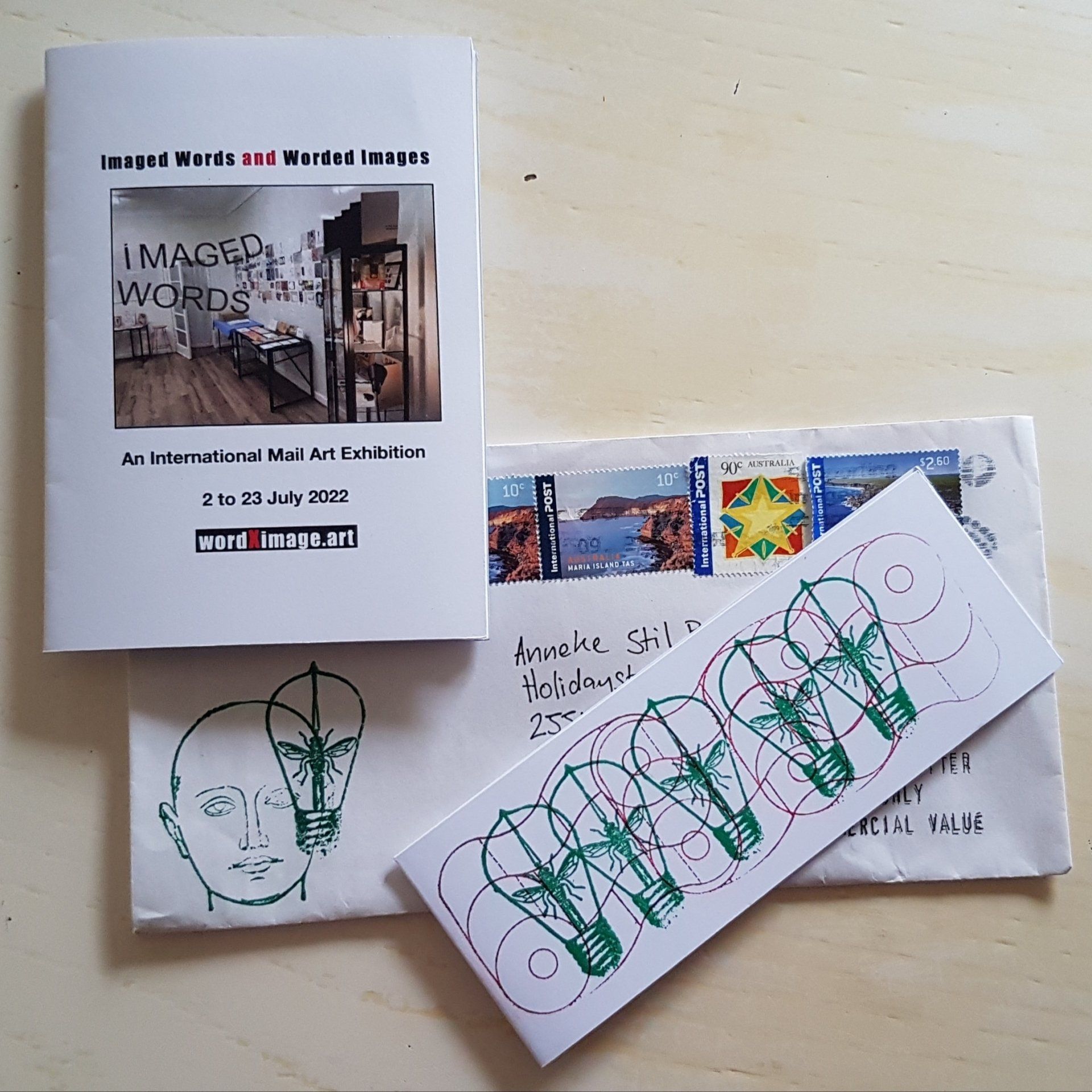 Een boekje, een envelop en een kaart met afbeeldingen. Het boekje bevat een foto en tekst, de envelop heeft postzegels en de kaart is versierd met gloeilampmotieven.