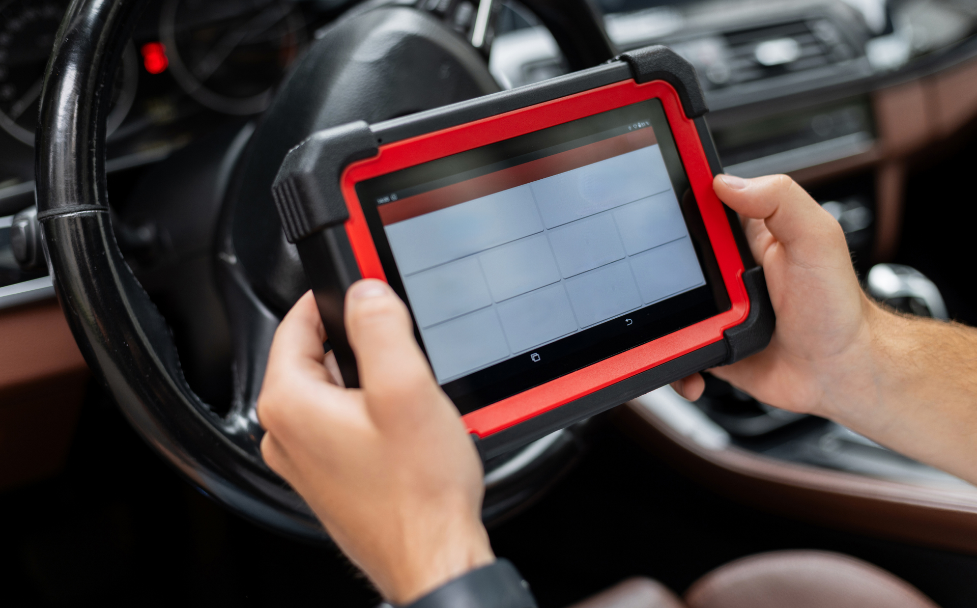 Hands using a diagnostic tablet inside a vehicle