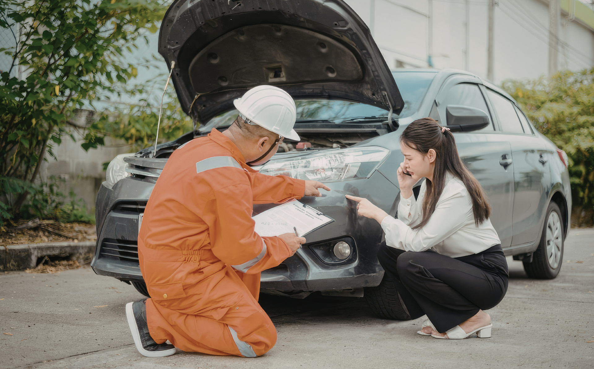 Mechanic and customer reviewing an engine with the hood open